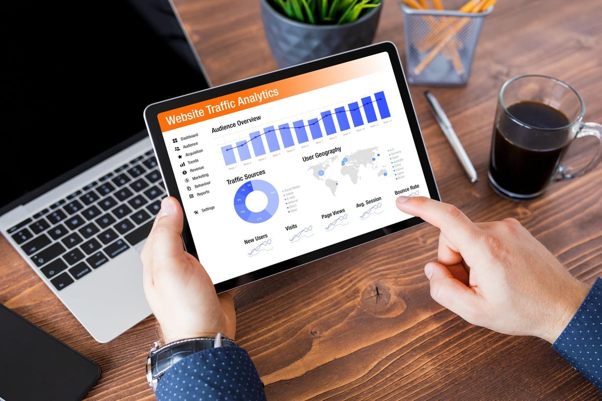 Person reviewing website performance analytics on a tablet, monitoring traffic and site data